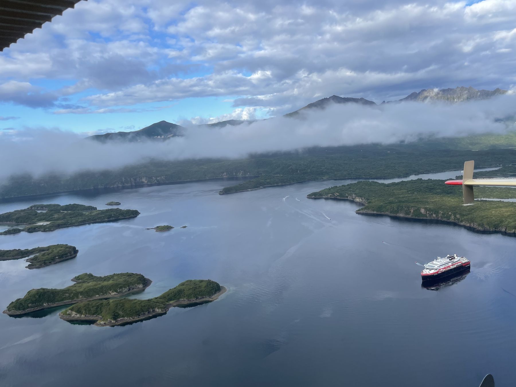 An expedition cruise ship among the islands of a bay on the Katmai coast, seen from the air