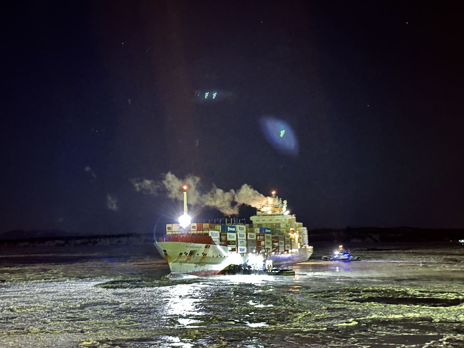 A container ship working through winter ice at night in Anchorage