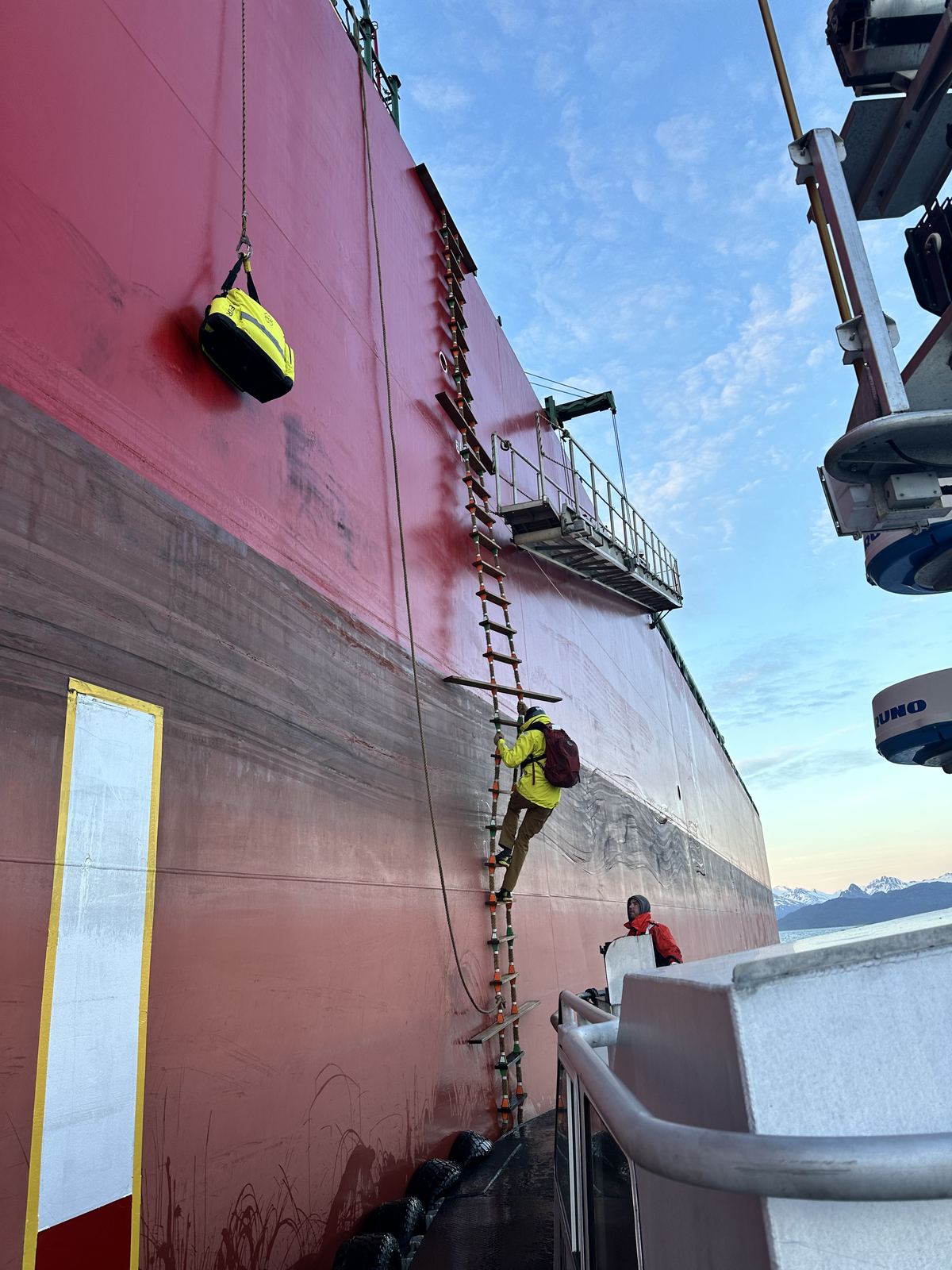 A pilot climbing a long pilot ladder up a tanker's side