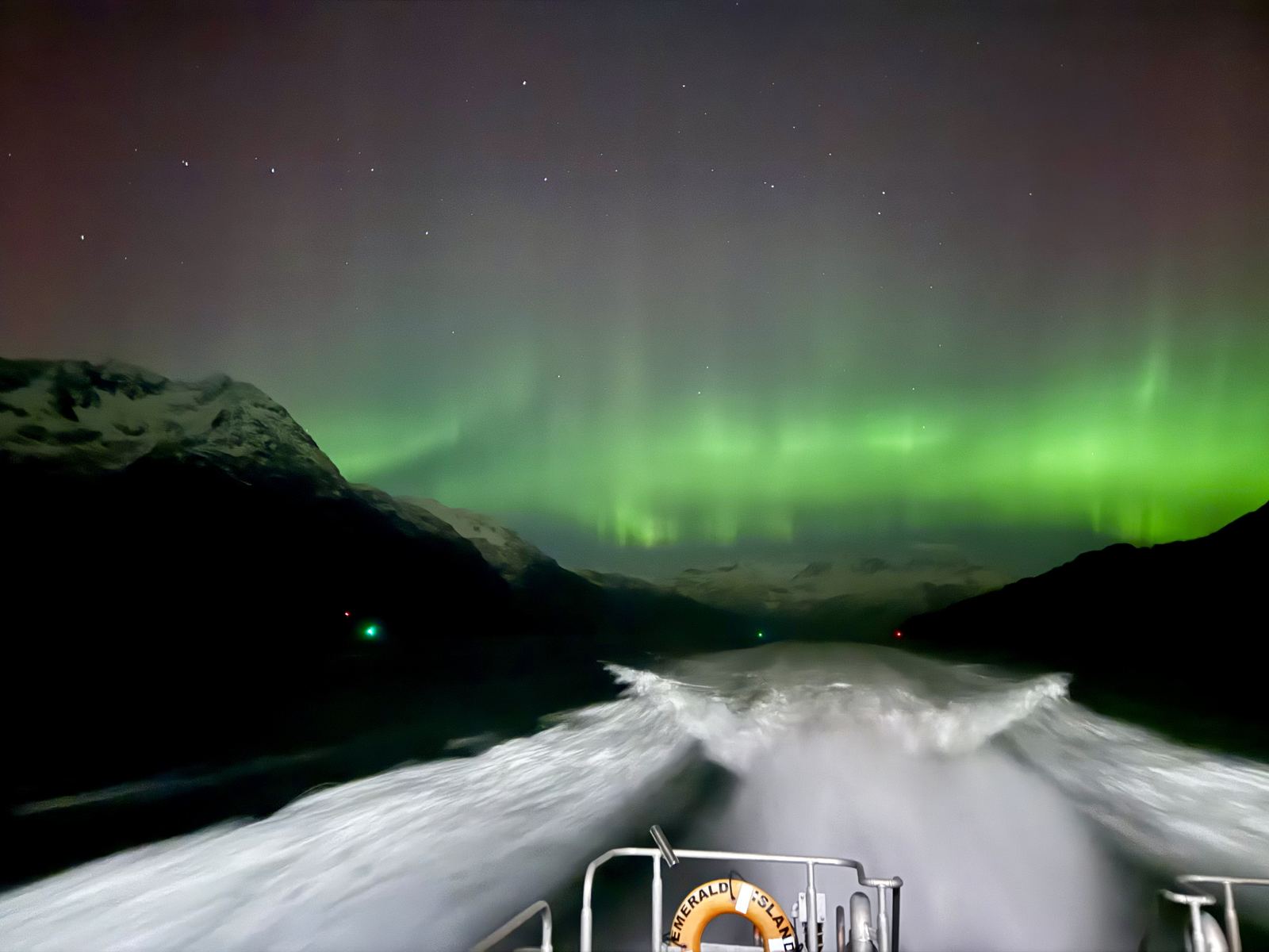 The pilot boat's wake at night under the northern lights in Valdez Arm