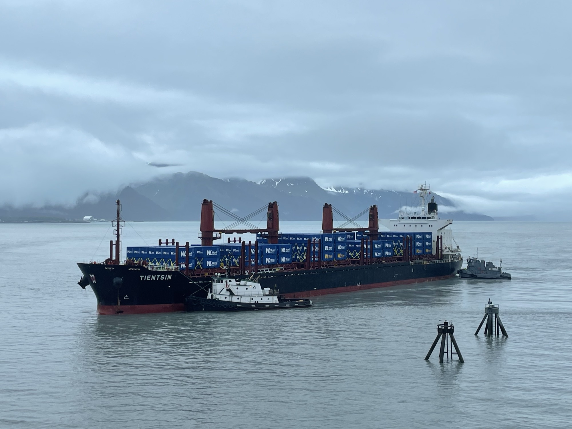 A tanker underway at dusk seen from a SWAPA pilot boat, with snow-capped mountains beyond