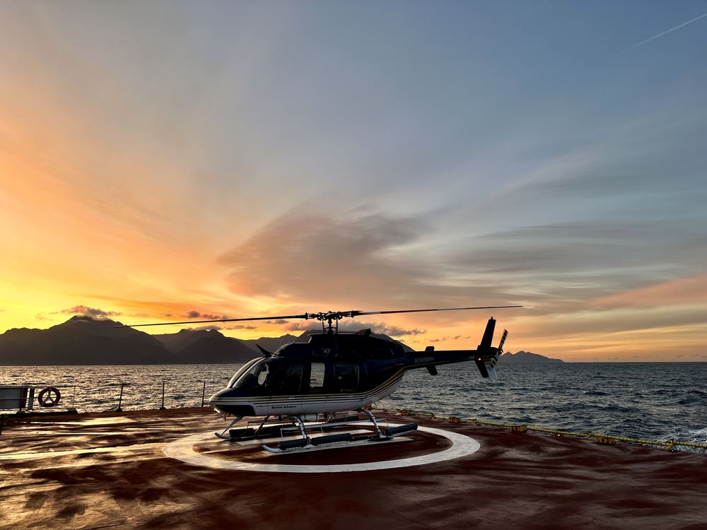 A helicopter on a ship's helideck at sunset in lower Cook Inlet